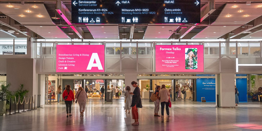 Öka din synlighet Besökare går genom en mässhall med digitala skyltar som visar Formex Talks och hall A på Stockholmsmässan.